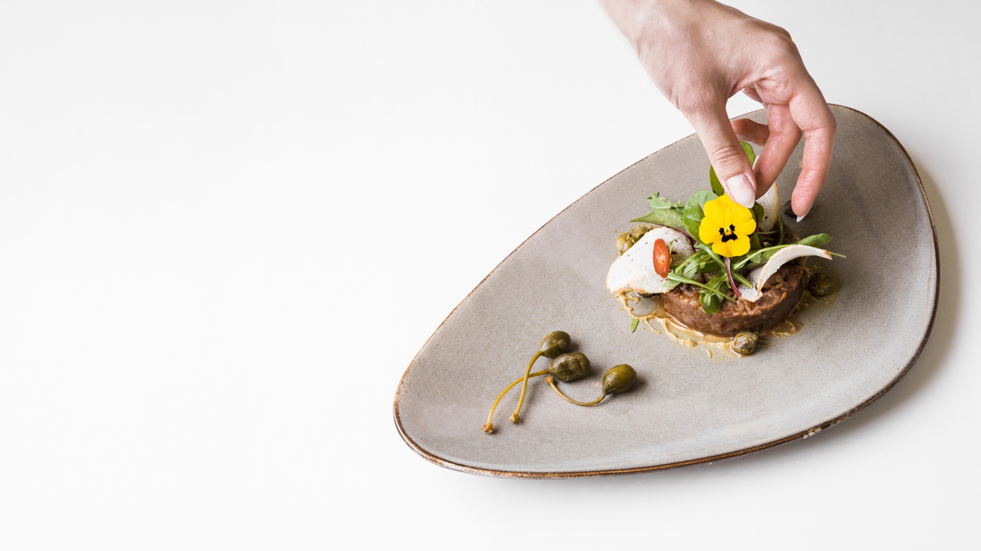 Chef arranging a plated dish on wooden table